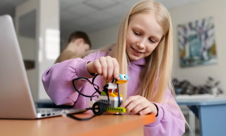 young-girl-using-laptop-electronic-parts-build-robot